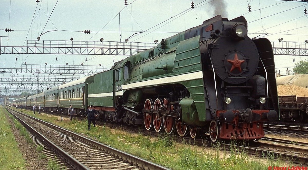 Glasnost und Perestroika machten es möglich: 1990 verkehrte ein Sonderzug für Eisenbahnfreunde von Brest durch das (damals noch sowjetische) Baltikum nach Leningrad. Auf der ersten Etappe von Brest nach Baranowitschi, wo auch das Foto am 04.06.1990 entstand, beförderte P36-0064 den Zug. Mit fast 30 m Länge und über 5 m Höhe wirken die Maschinen mit der Achsfolge 2'D2' für einen Mitteleuropäer ziemlich beeindruckend. Die bis zu 125 km/h schnellen Lokomotiven mit einem Dienstgewicht von 245 t wurden von Kolomna in einer ungefähren Stückzahl von 250 Exemplaren zwischen 1949 und 1956 gebaut und u. a. zwischen Moskau und Leningrad sowie auf der Transsib eingesetzt. Die letzten waren bis etwa 1974 im Plandienst.
