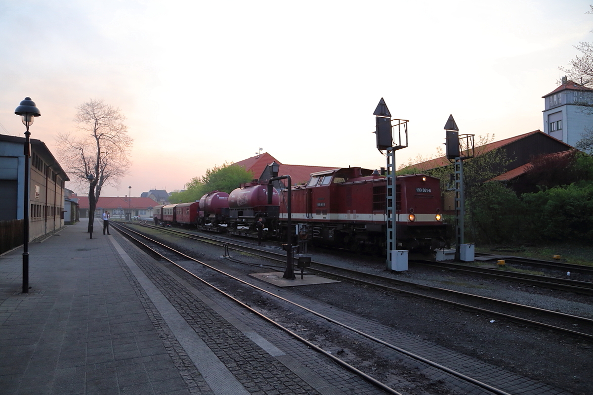 HSB-Bahnhof Wernigerode am Morgen des 21.04.2018. Der zur Abfahrt bereitstehende GmP, bei welchem es sich, streng genommen, eigentlich um eine Dienstfahrt handelt, ist nur einmal jährlich, jeweils im Frühjahr, zu sehen. Hierbei gilt es zwei  Schienenfeuerwehren  welche aus zwei Rollwagen mit aufgebockten Regelspurkesselwagen, die mit Löschwasser gefüllt und mit eigener Pumpe und Löschutensilien versehen sind, nach Drei Annen Hohne bzw. zum Brockenbahnhof zu bringen, wo sie während des Sommers (Waldbrandsaison)stationiert werden um z.B. durch Funkenflug der Dampfloks verursachte Böschungsbrände schnell bekämpfen zu können. Der Vorteil dieser Löschfahrzeuge besteht darin, daß sie auch an für herkömmliche Feuerwehren unzugänglichen Stellen eingesetzt werden können. Im Bedarfsfall übernimmt kurzerhand die Lok eines in der Nähe befindlichen Reisezuges den Löschwagen und fährt mit ihm zum Einsatzort.
Wozu sind jedoch die Reisezugwagen, aus welchen der zweite Teil des Zuges besteht? Nun, man hat sich bei der HSB GmbH gefragt:  Wenn wir ohnehin diesen Zug fahren, warum nicht auch Fotografen mitnehmen und ein paar Scheinanfahrten einbauen?  Und schon hatte man einen fotogenen Sonder-GmP unter dem Motto  HSB läßt es kesseln , welcher sich regen Interesses erfreute. Als Zugeständnis an die Fotografen wurden, obwohl man bereits in Drei Annen Hohne einen der Feuerlöschwagen hätte aus dem Zugverband rangieren können, beide Kesselwagen mit hinauf zum Brocken genommen, da dies den Schauwert ja doch beträchtlich erhöhte. Der Packwagen diente übrigens als sogenannter  Schutzwagen .