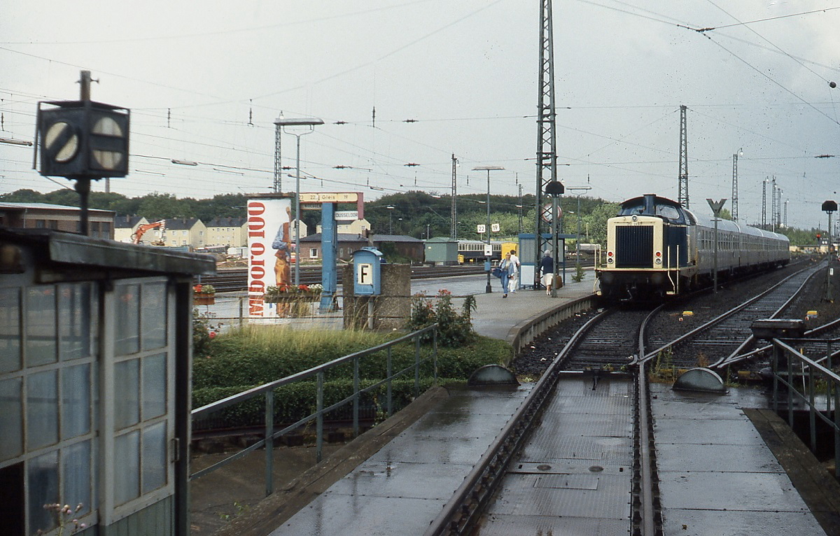 Im Bahnhof Düren wartet Mitte der 1980er Jahre eine 212 mit ihrem Nahverkehrszug nach Düsseldorf auf Fahrgäste. Die Drehscheibe im Vordergrund diente früher zum Wenden der Dampflokomotiven, aus Platzgründen konnten hier keine Weichen verlegt werden. Die unter Denkmalschutz gestellte Drehscheibe blieb erhalten, während die Gleise inzwischen abgebaut wurden.