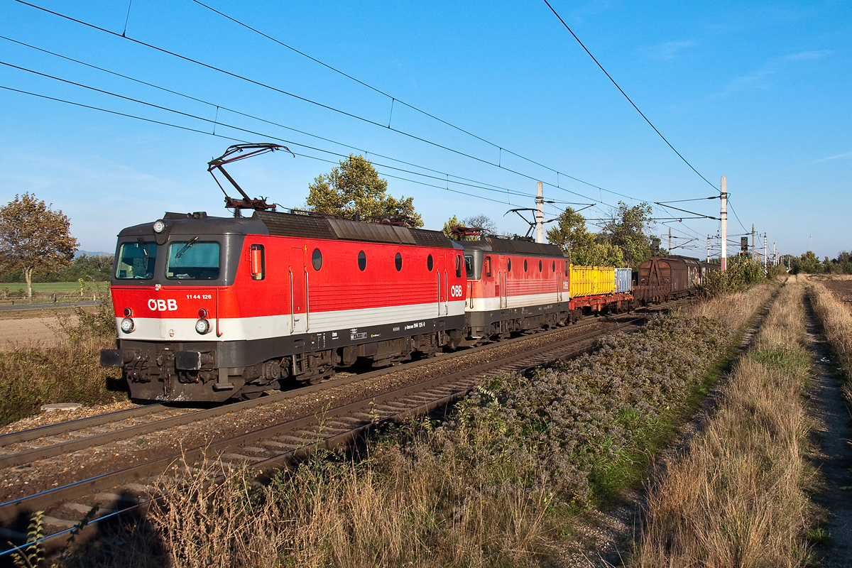 Im schnen Morgenlicht fahren 1144 126 und 1144 279 mit einem Gterzug in Richtung Osten. Die Aufnahme entstand am 04.10.2013 kurz nach dem Bahnhof in Himberg.