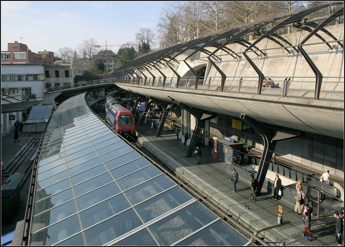 In den Hang integriert -

Blick vom Fußgängersteg auf den in den Hang eingebauten Bahnhof Stadelhofen. An dieser Strecke verzweigt sich die durch den Hirschgrabentunnel kommende S-Bahnstrecke nach Süden in Richtung Rapperswil und nach Osten durch den etwa 4,9 km langen Zürichbergtunnel nach Stettbach. Übrigens wurde ein weiterer, unterirdischer Zwischenbahnhof zwischen Hauptbahnhof und Stadelhofen von den Bürgern abgelehnt. 

09.03.2008 (M)