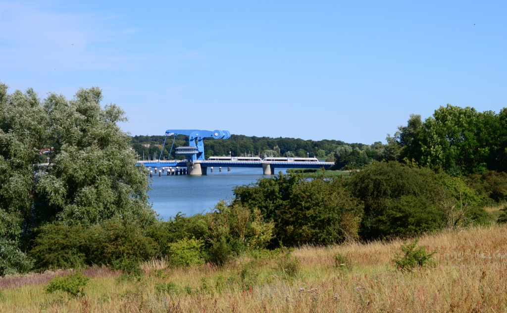 In der Nähe des kleinen Ortes Sauzin hat man einen guten Blick auf die Klappbrücke von Wolgast. UBB 29414 nach Züssow überquert diese gerade. 22.07.2016