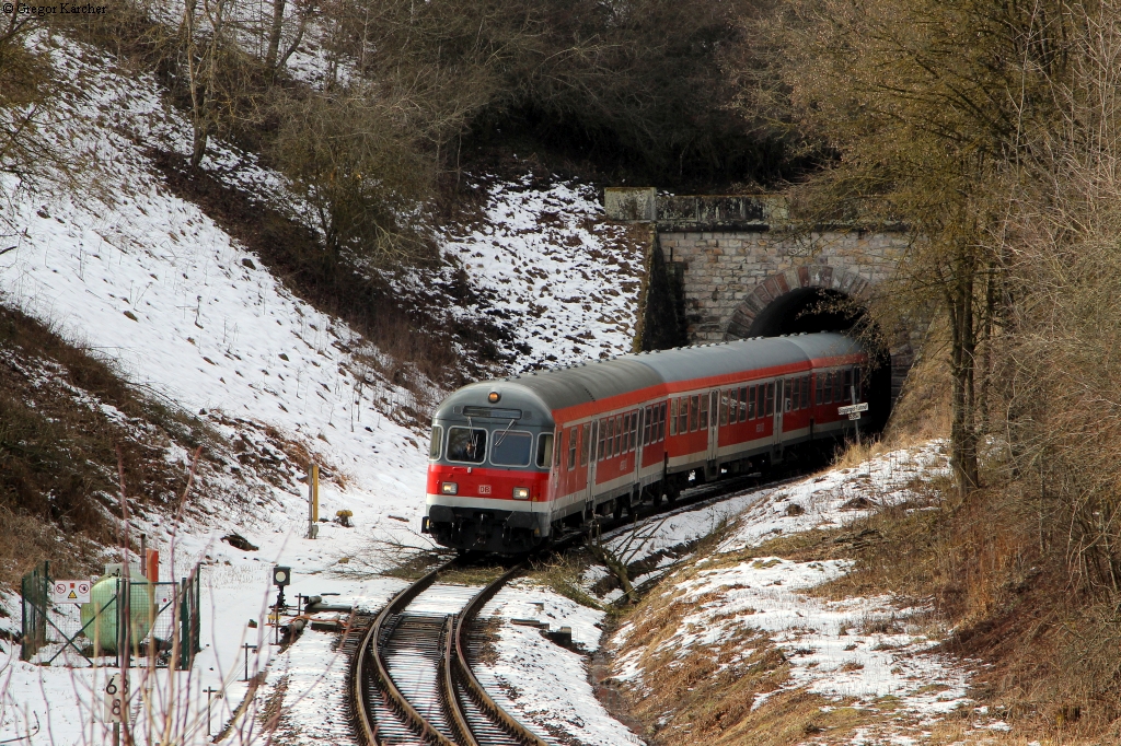 IRE 3215 mit Schublok 218 495 kommt aus dem 535 Meter langen Dögginger Eisenbahntunnel heraus. Aufgenommen am 01.03.2014 in Döggingen.