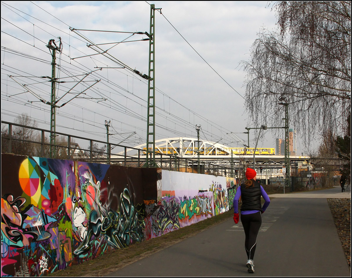 Joggen entlang der Fernbahn -

Die Bereiche um das Gleisdreieck und auf der Ostseite der Fernbahnstrecke wurden zu P Parkanlagen gestaltet. Dieser Park setzt sich aus dem Park am Gleisdreieck und dem Flaschenhals Park zusammen, alles weitgehend frühere Bahnanlagen. 

Das Bild wurde zwischen der Yorkstraße und dem U-Bahnhof Gleisdreieck aufgenommen. Die Betonwand links wurde für Graffiti freigegeben.

Im Hintergrund ein U-Bahnzug der Linie U2 der gleich die Station Gleisdreieck erreichen wird. Darunter, rechts neben der Joggerin die Einfahrt in den Nord-Süd-Fernbahntunnel.

Berlin, 28.02.2016 (M)