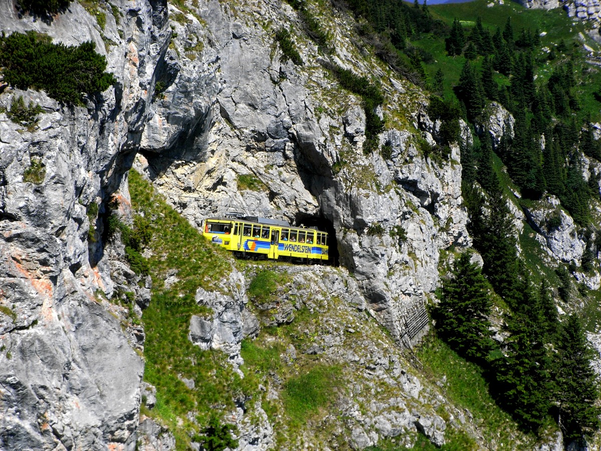 Kurz unterhalb des Bergbahnhofs kann man am 23.06.2013 den talwärts fahrenden Triebwagen der Wendelsteinbahn erblicken bevor er wieder im nächsten Tunnel verschwindet.