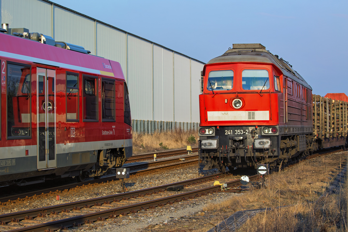 Lok 241 353 auf dem Bahnhof Torgelow vor einem Holzzug und links ist der einfahrende DB Lint 41 (Szczecin) mit Spiegelung der EBS Lok zu sehen. - 10.02.2017