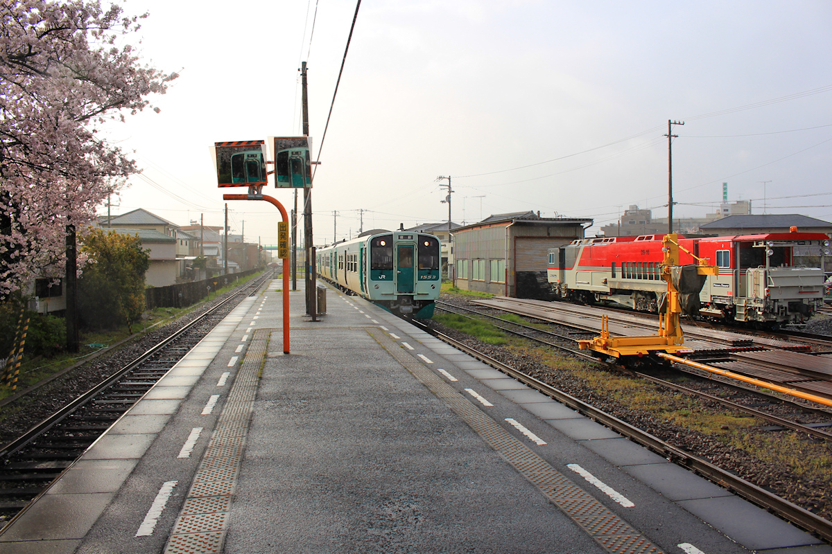 Lokalverkehr auf Shikoku - der Nordosten: In der feuchten Morgenatmosphäre trifft neben einer grossen Plasser&Theurer Gleisinstandstellungsmaschine ein Dreiwagenzug (geführt vom neuen Triebwagen Serie 1500 Nr.1553) in Hanoura ein. 3.April 2015.  