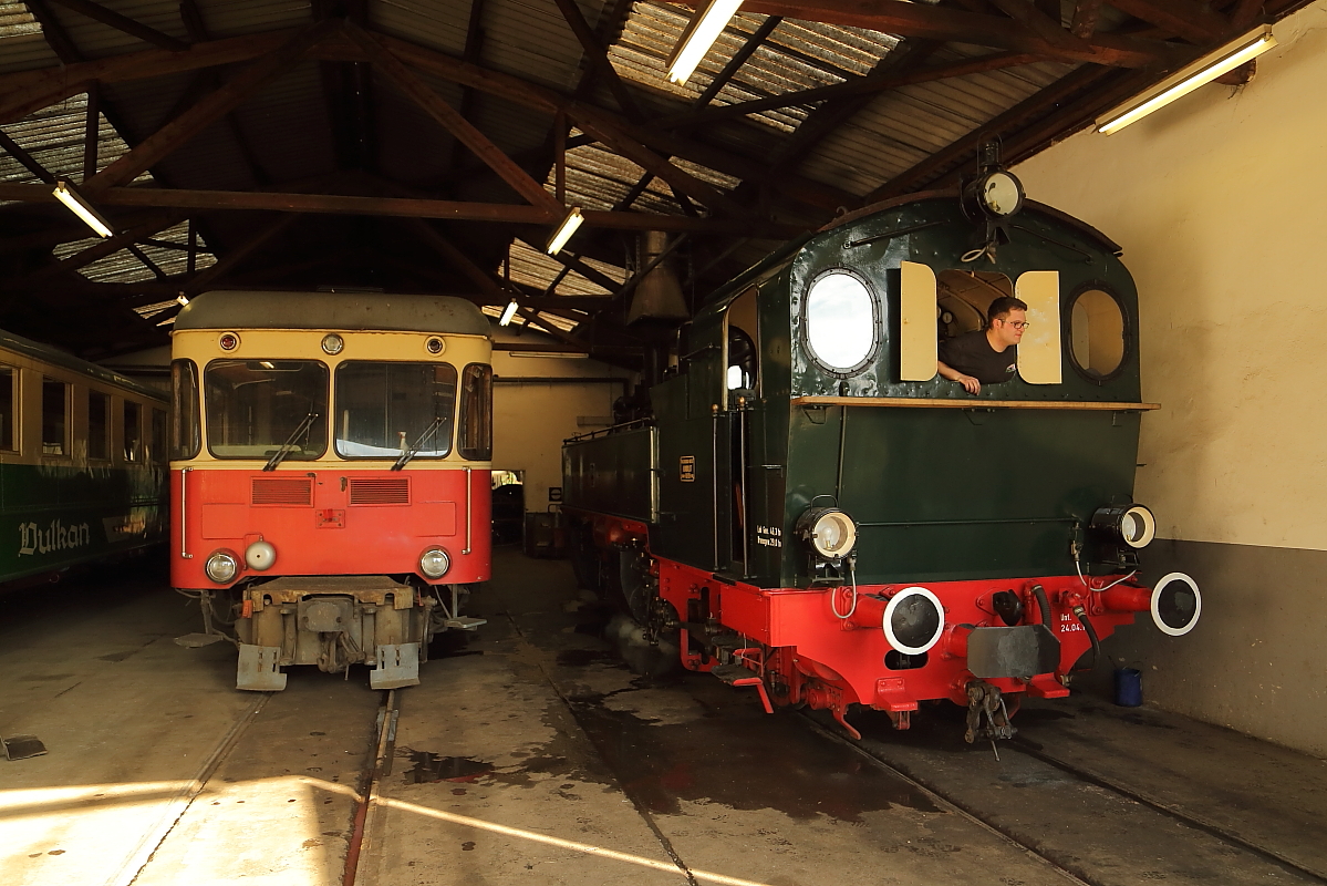 Lokschuppen der Brohltalbahn am Morgen 05.06.2015. Links ist Schlepptriebwagen VT 30 zu sehen, welcher 1956 von der Fa. Fuchs in Heidelberg unter der Fabriknummer 9053 gebaut wurde. Er verfügt über 4 Büssing-Dieselmotoren der Bauart U 11 D mit je 170 PS und erreicht eine Höchstgeschwindigkeit von 60km/h. Seit 2009 ist er wegen Fristablauf abgestellt. Rechts wird die erst kürzlich wieder in Dienst gestellte Mallet-Dampflok 11sm auf einen Sonderzugeinsatz vorbereitet. (Das Gelände und der Lokschuppen waren im Rahmen einer Fotoveranstaltung frei zugänglich!)