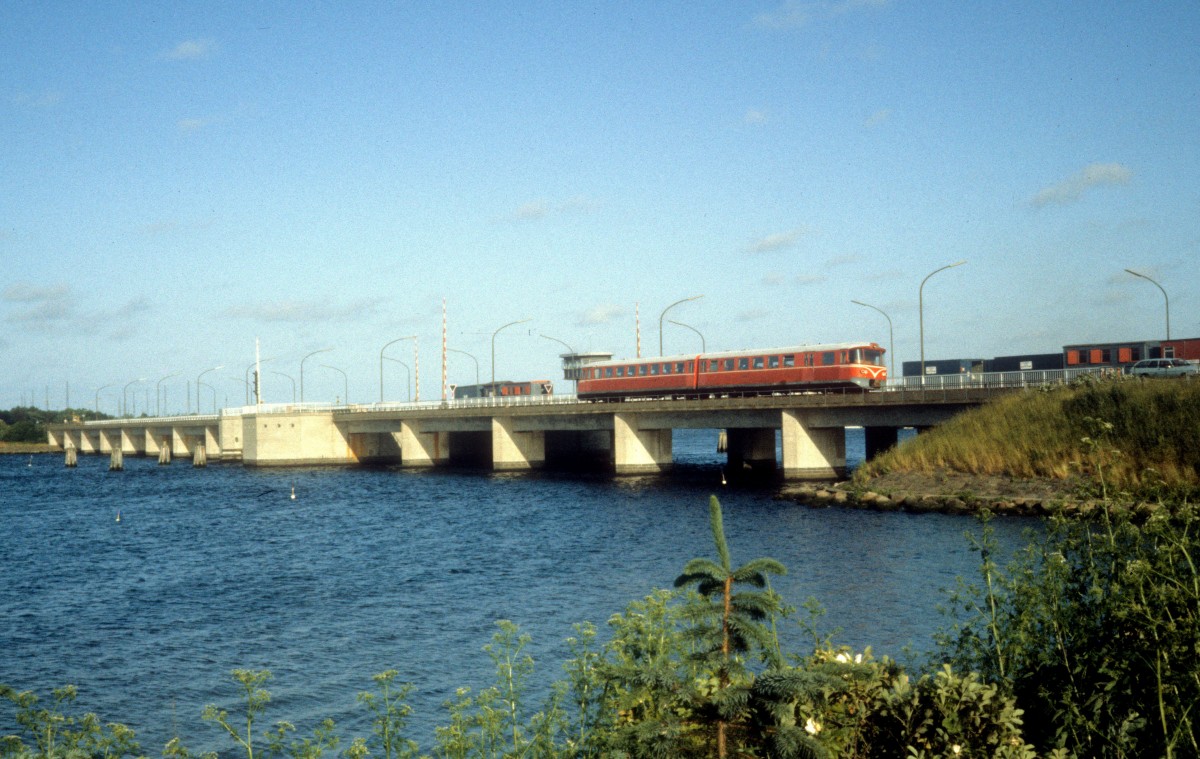Lollandsbanen (LJ): En Triebzug (Ym + Ys) fährt am 22. Juni 1983 über die Kong Frederik den IXs Bro (: Die Brücke-des-König-Frederiks-des-Neunten), die die Inseln Falster und Lolland verbindet. Der Zug wird in Kürze den Bahnhof Nykøbing Falster erreichen.
