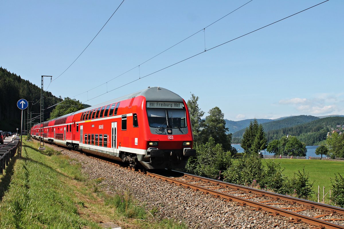 Mit dem Titisee im Hintergrund fuhr am Morgen des 30.07.2017 der D-DB 50 80 80-35 367-7 (Bauart: DABpbzfa 762) zusammen mit der Schublok 146 233-2  Donaueschingen  als RB (Seebrugg - Freiburg (Brsg) Hbf) die Seesteige hinab in Richtung Bf Titisee.