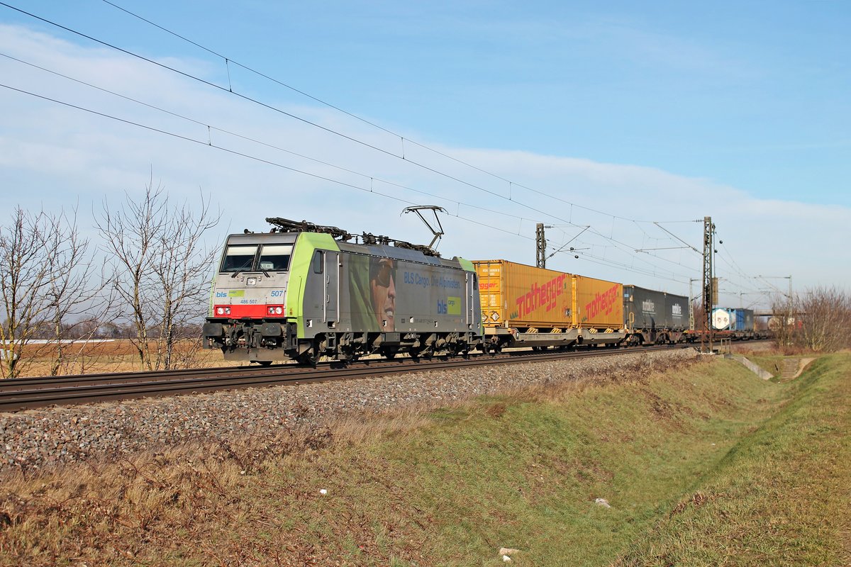 Mit einem bunten Containerzug war am 22.12.2016 die Re 486 507 auf der KBS 703 bei Hügelheim in Richutng Schweizer Grenze unterwegs.