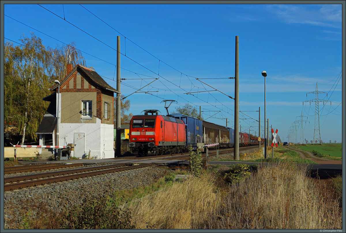 Mit einem gemischten Güterzug rollt 145 032-0 an der Blockstelle Braschwitz vorbei, die auch gleichzeitig den örtlichen Bahnübergang bedient. (31.10.2018)