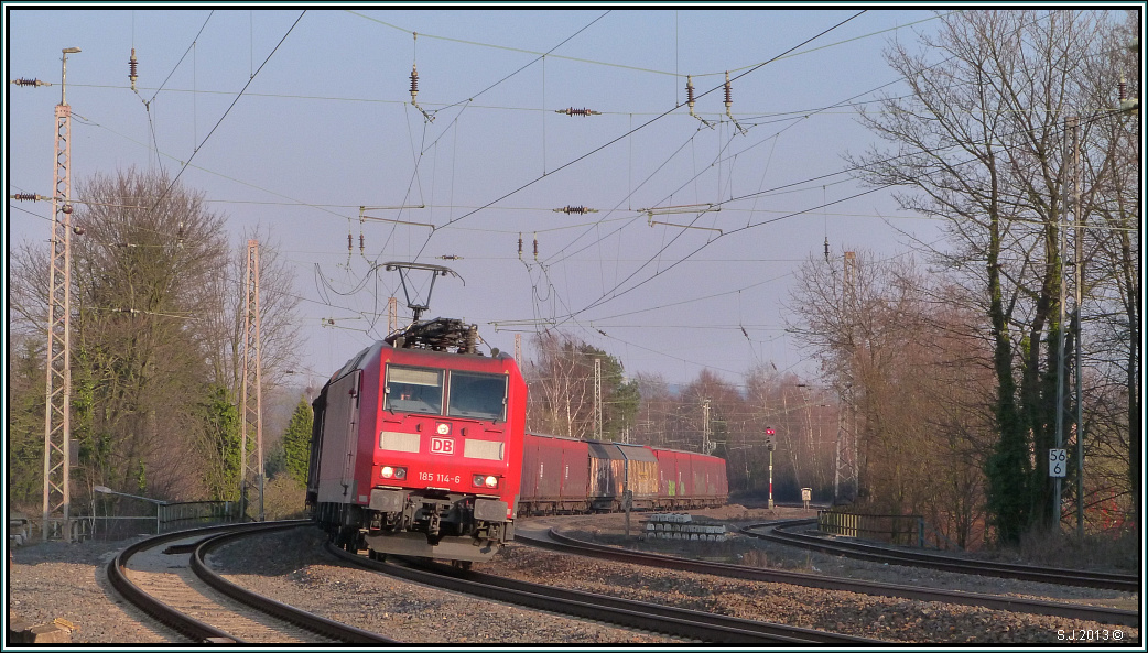 Mit ihrer Gterfracht am Haken legt sich die 185 114-6 in den Gleisbogen bei Eschweiler (Rhl). Fahrziel ist Aachen West. Bildlich festgehalten im April 2013.