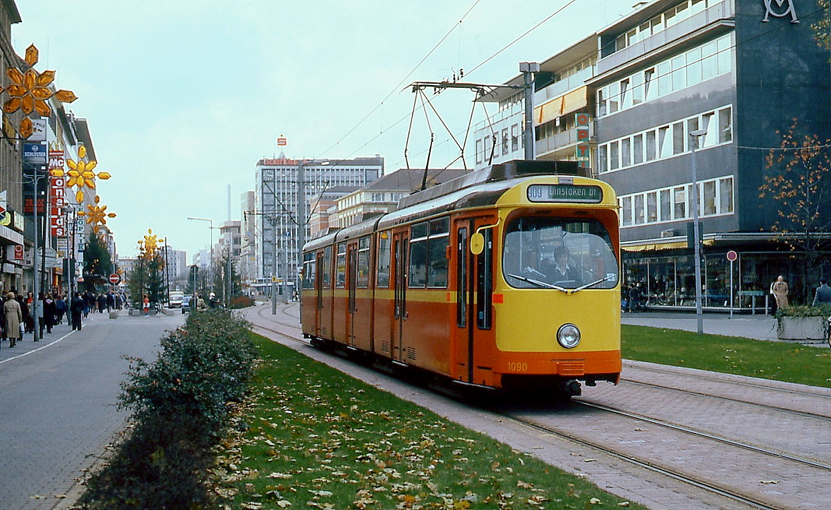 Mitte der 1980er Jahre wurde die Königstraße in Duisburg zur Fußgängerzone umgestatltet. Bis zur Aufnahme des Tunnelbetriebes am 11.07.1992 verkehrte hier die Straßenbahn, wie hier der Duewag-Tw 1090 als Linie 909 nach Dinslaken an einem Spätherbsttag in der zweiten Hälfte der 1980er Jahre