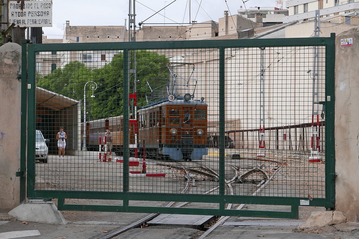 Nach dem Zurücksetzen des Triebwagens wird das Tor zum Betriebs-/Bahnhofsgelände der Ferrocarril de Sóller in Palma de Mallorca wieder geschlossen. Triebwagen Nr. 3 steht am 18.09.2016 mit seinen angehängten Wagen bereit zur nächsten Abfahrt nach Sóller.