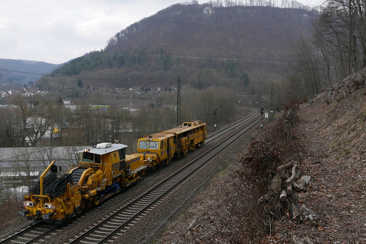 Nicht weit von ihrem Heimatstandort Göppingen entfernt sind eine Schotterplanier- sowie Stopfmaschine von Leonard Weiss, als diese am 12.03.2016 in Geislingen/Steige am Fotograf vorbeifahren.