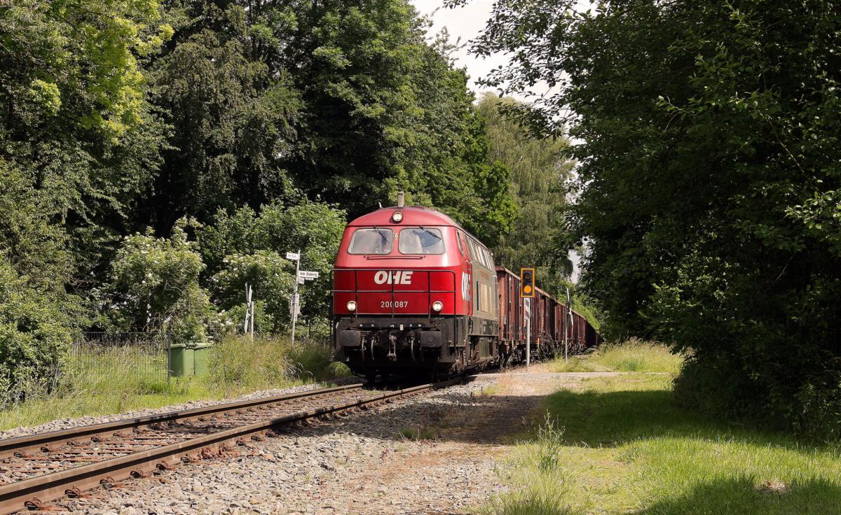 OHE Lok 200087 war am 5.6.2014 auf der Georgsmarien Hütten Eisenbahn im Einsatz.
Hier hat sie gerade mit einem Leerzug den Scheitelpunkt der Strecke bei Holzhausen- Patkenhof erreicht. Von nun an geht es bergab weiter nach Hasbergen.