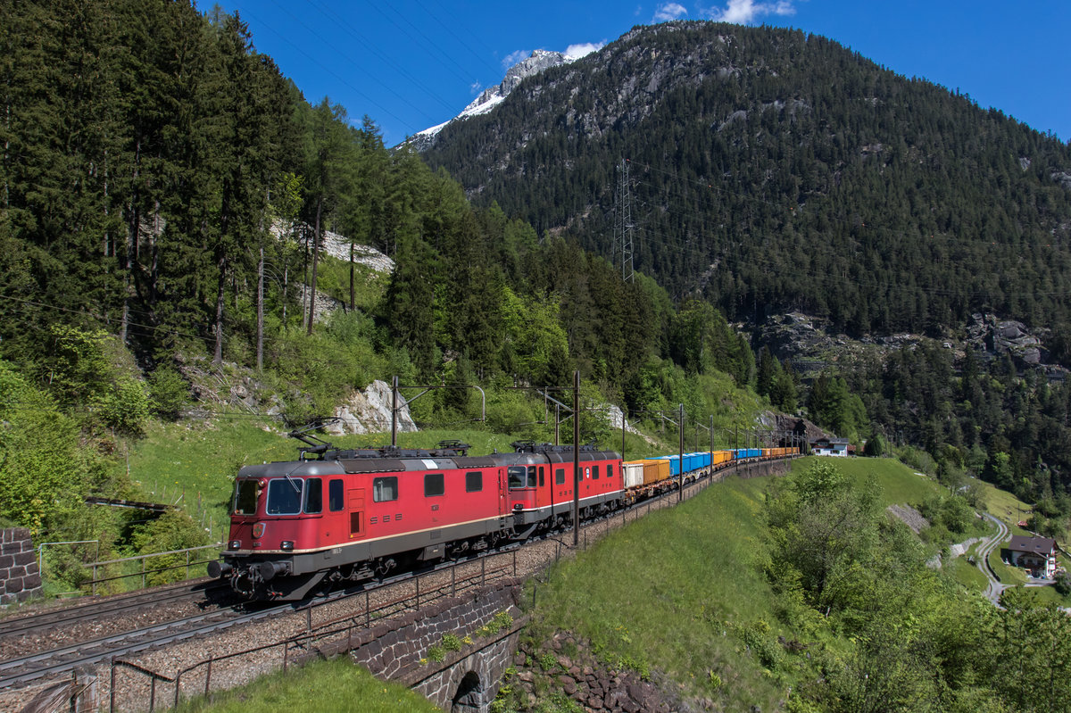 Re 4/4-11263 und Re 6/6-11627 fahren mit einem bunten Kieszug auf der dritten Ebene bei Wassen in Richtung Göschenen, aufgenommen am 25. Mai 2016.