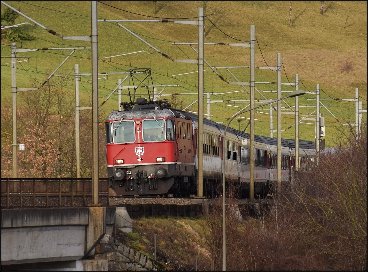 Re 4/4 II 11131 der ersten Serie passt gerade eben zwischen die Masten bei der Talberquerung in Bckten. Januar 2018.