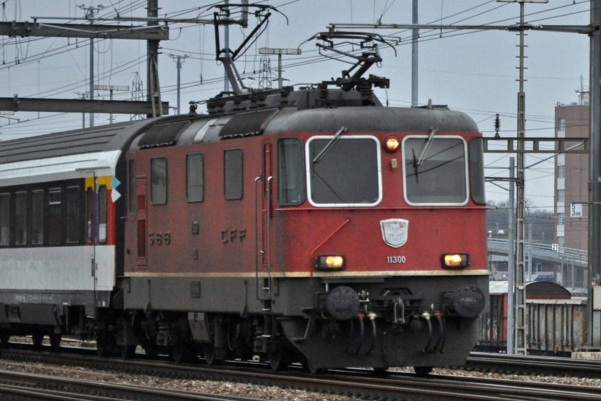 Re 4/4 II 11300 durchfährt den Bahnhof Muttenz. Die Aufnahme stammt vom 29.01.2014.