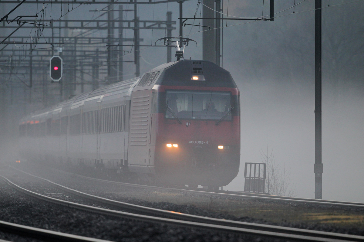 Re 460 085-4 braust mit einem IC von Chur nach Zürich HB bei Bodennebel in Weesen vorüber.Der rechte Scheinwerfer dürfte da mal ersetzt werden...Bild vom 14.11.2014