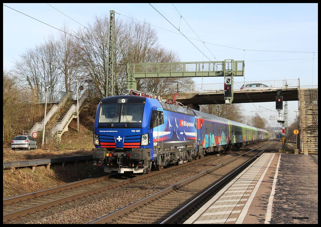 SBB Cargo 193492 Vectron durchfährt hier mit dem Flix Train nach Köln den Bahnhof Hasbergen am 17.02.2019 um 15.00 Uhr.

Anmerkung zum empfohlenen Geraderichten
Da die Straßenbrücke in Natura ansteigt und die Treppe rechts schräg zur Brücke hin verläuft, ist hier mit Geraderichten nichts zu machen! Auch die Lampe an der linken Treppe habe ich nicht schräg gestellt!!!
Man achte mal auf den senkrecht stehenden rechten hinteren Masten! Nach Prüfung mit einem Geodreieck muss das alles so bleiben! Da würde Geraderichten eher mal schaden!