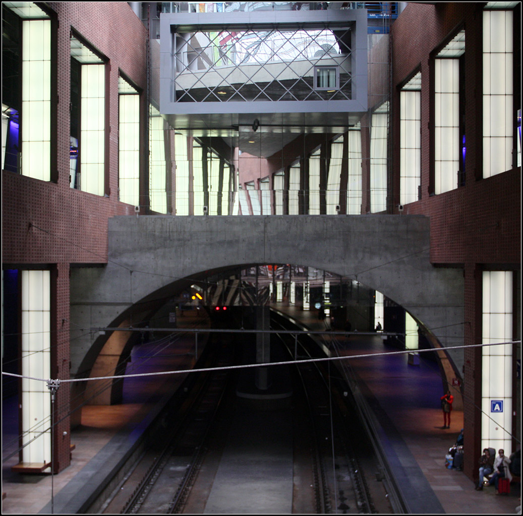 Spiegel und Betonbögen über den Bahnsteiggleisen -

Blick von einer Zwischenebene hinunter auf die mittleren der vier Durchgangsgleise in der unteren Bahnsteigebene. Die zwei roten Punkte im Bogen sind die Rücklichter eines Thalys-Zuges, der hier Antwerpen Centraal in Richtung Brüssel verlässt. Hinten den beleuchteten Wandöffnungen oben befinden sich die Gleise 11 bis 14 der Ebene -1.

18.06.2016 (M)