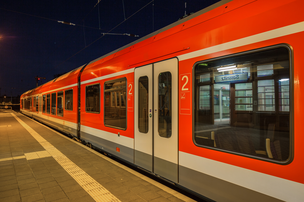 Spiegelung von Bahnhofsschild und Empfangshalle im Seitenfenster von RE 9, der in Sassnitz am Bahnsteig steht. - 17.09.2016
