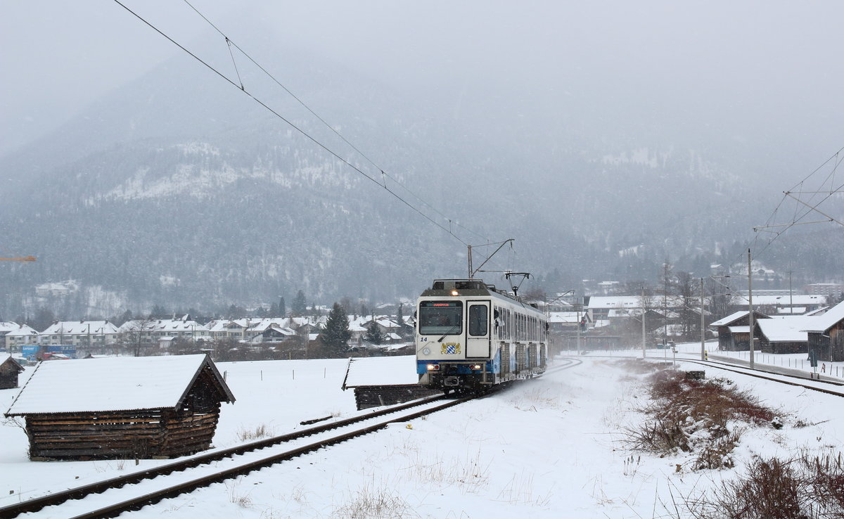 Triebwagen Nummer 14 - ein Doppektriebwagen - der Bayrischen Zugspitzbahn hat den Bahnhof von Garmisch-Partenkirchen verlassen. Die Strecke der Bayrischen Zugspitzbahn verläuft anfangs parallel zu dem Gleis der Außerfernbahn. In dem Freiraum zwischen dem linken Gleis der Zugspitzbahn und dem rechten Gleis der KBS 9xx hat früher mal ein Gleis gelegen, welches Zügen aus Richtung Kempten/Reutte einen direkten Zugang ins Bahnbetriebswerk ermöglichte. Weder das Gleis, noch das BW sind heute noch erhalten. Die DB hat das Gelände verkauft. Es sollen riesige Hotelanlagen entstehen...

Garmisch-Partenkirchen, 20. März 2018