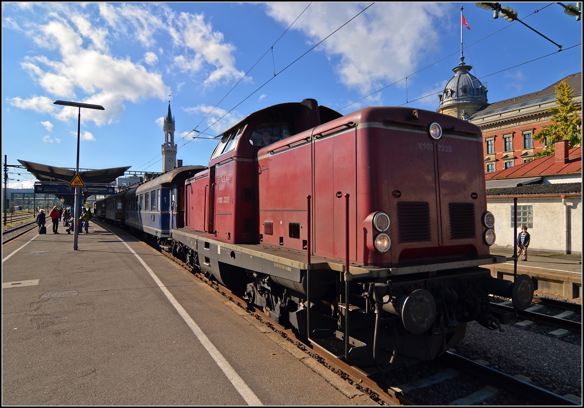 <U>150 Jahre Hochrheinbahn.</U>

V100 2335 wartet am Endpunkt der Badischen Hauptbahn, in Konstanz, auf die Abfahrt rheinabwärts. Mit ihrem historischen Eilzug steht sie vor der Kulisse von Bahnhofsturm und ehemaliger Oberpostdirektion. Oktober 2013.