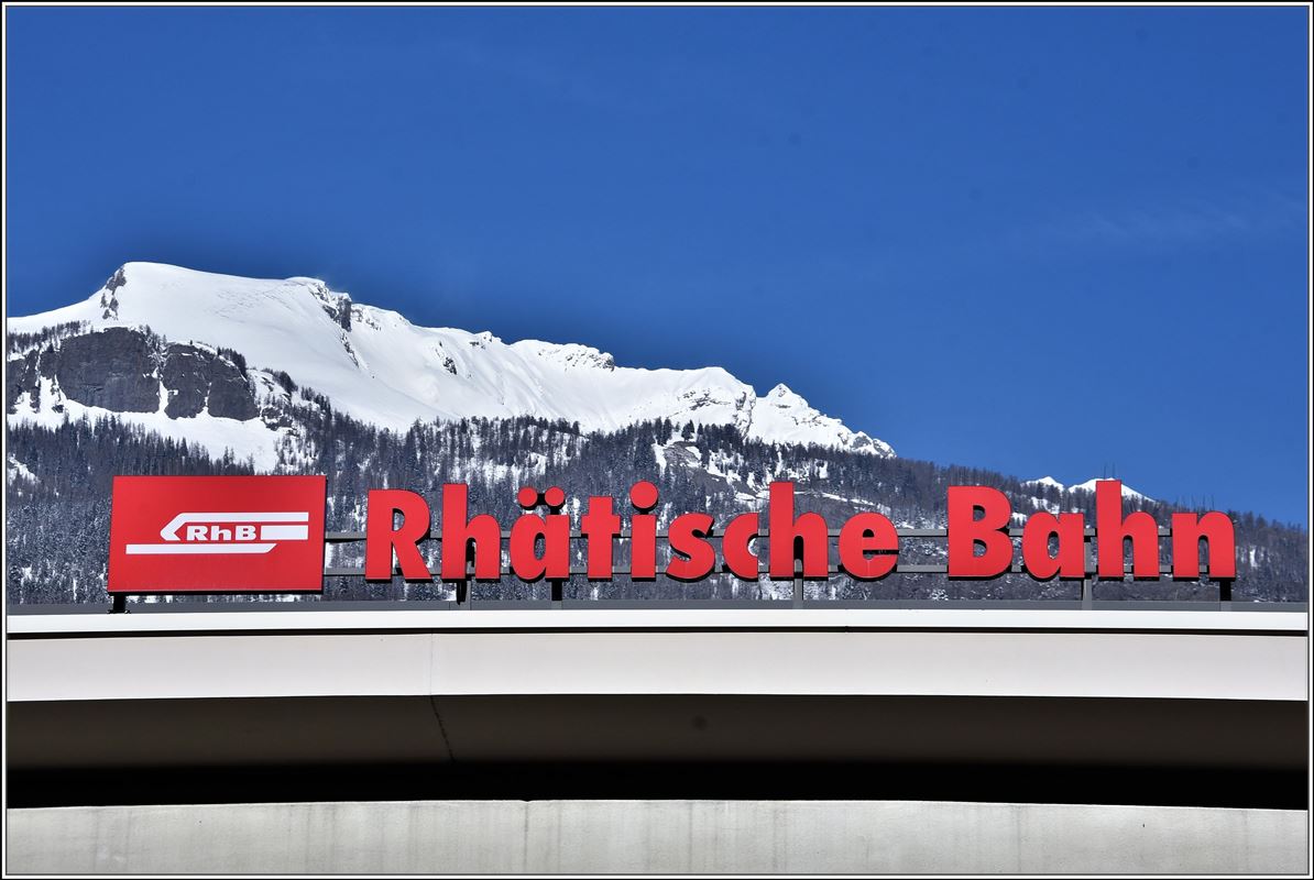 Unübersehbar auf dem Churer Bahnhofgebäude das Logo der RhB vor dem Haldensteiner Calanda 2806m ü/M. (22.03.2018)