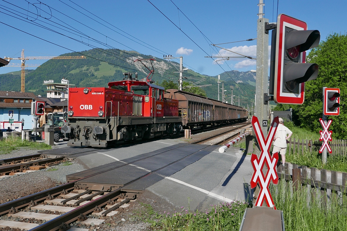 Von einem in der Nähe liegenden Industriebetrieb kommend schiebt 1063 046-5 einen Güterzug in den Bahnhof von St. Johann in Tirol (26.05.2017).