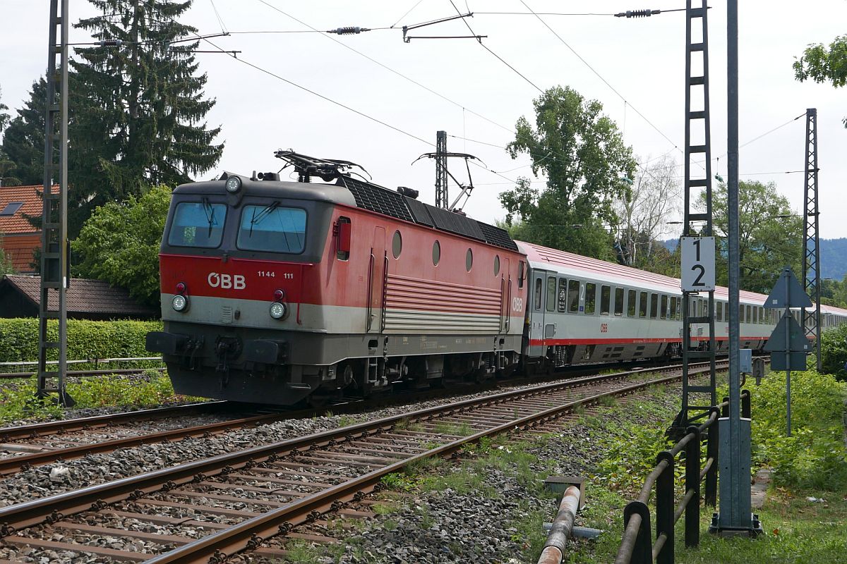 Von Innsbruck kommend hat 1144 111 die Wagen des IC 118 am Haken und erreicht in Kürze den Lindauer Inselbahnhof, wo zwei Loks der Baureihe 218 die Wagen übernehmen werden. Am 11.08.2018 wurde am Bahnübergang Hasenweidweg auf den Auslöser gedrückt.