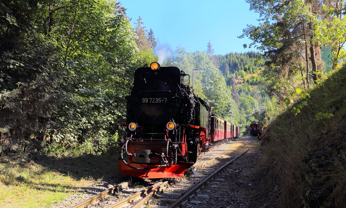 Vorbeifahrt von 99 7235 mit P8964 (Eisfelder Talmühle - Quedlinburg) am 07.07.2018 am Unterberger Steinbruch. (Bild 3) Sehr schön ist hier auch die erhebliche Steigung der Strecke zu sehen, bei welcher zwischen Eisfelder Talmühle und Birkenmoor auf gerade mal 6 Kilometer 181 Höhenmeter überwunden werden müssen.