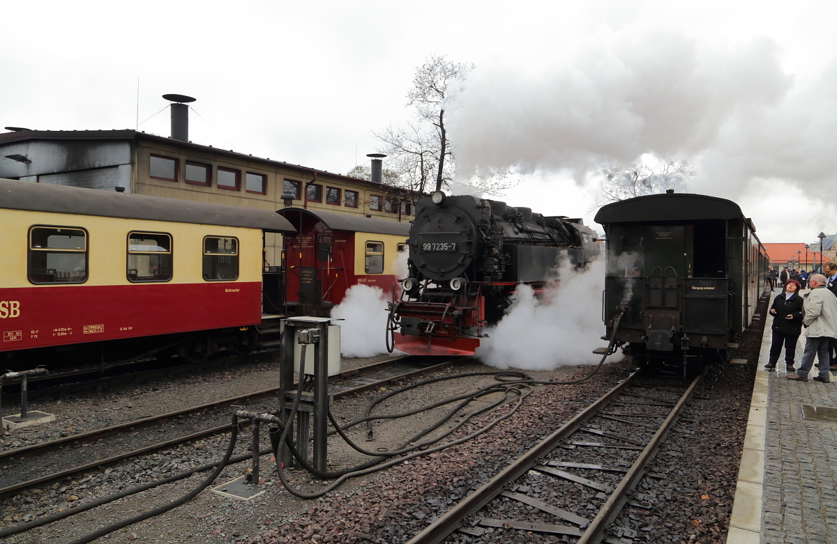 Während sich am Mittag des 16.10.2015, auf dem Bahnsteig rechts (Gleis 33), langsam die Fahrgäste des IG HSB-Sonderzuges versammeln, um mit diesem zum Brocken zu fahren, hat derweil 99 7235 von ihrem links stehenden Planzug P 8932, welchen sie gerade vom Brocken zurückgebracht hat, abgekuppelt und ist jetzt unterwegs ins Bw.