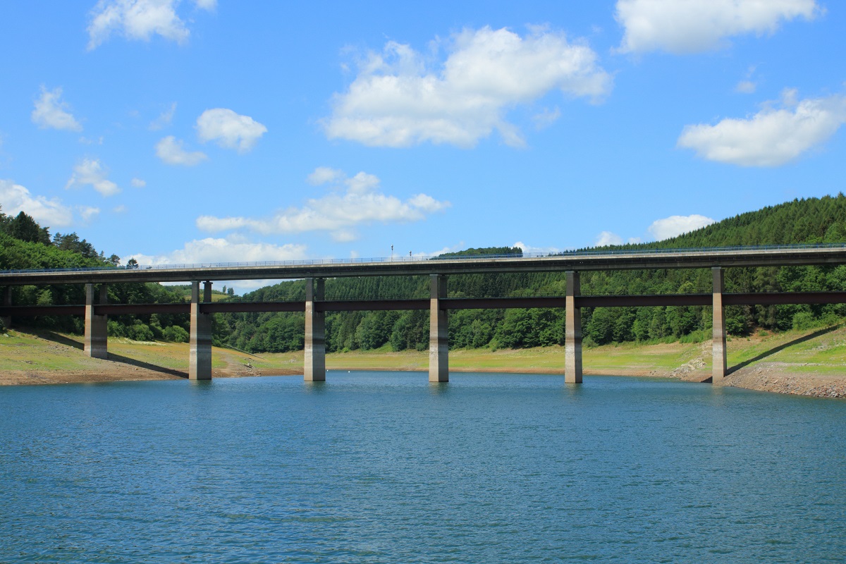 Wegen Sanierungsarbeiten am Haupt- und Vordamm musste der Wasserstand im Biggesee in diesem Sommer um fünfzehn Meter abgesenkt werden. Dadurch entsteht ein ganz anderer Blick auf die Brückenbauwerke, wie hier die kombinierte Eisenbahn-/Straßenbrücke über das Dumetal (06.07.2015). Leider wird auch die Bahnstrecke von Finnentrop nach Olpe saniert, daher verkehren während der Sommerferien in Nordrhein-Westfalen keine Züge.