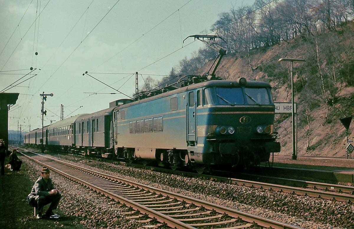 Wenig Beachtung bei den Eisenbahnfotografen findet die 1603 der SNCB, die Anfang April 1976 mit einem Schnellzug nach Köln den Bahnhof Stolberg durchfährt. Ihr Blick ist Richtung Bahnhof gerichtet, denn dort steht ein mit einer Dampflok der Baureihe 50 bespannter Sonderzug, der anlässlich des Dampflokabschiedes des Bw Stolberg nach Aachen fahren wird.