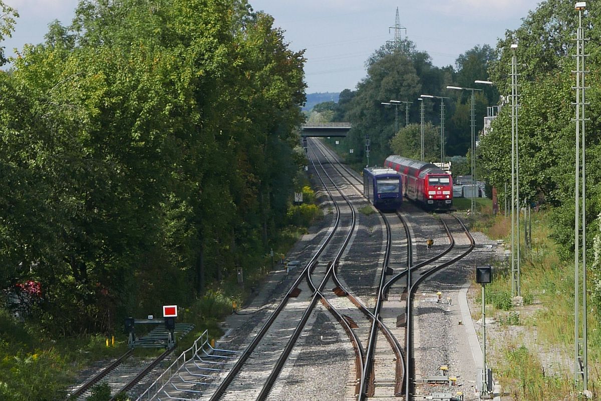 Wenn auf Grund von Gleisbauarbeiten die Bahnstrecke in einem Bahnhof endet und beginnt, in dem nur ein Gleis für den Personenein-/-ausstieg zur Verfügung steht und zwischen Ankunft und Abfahrt eine halbe Stunde liegt, in der ein anderer Zug ebenfalls auf diesem einzig befahrbaren Gleis ankommt/abfährt, muss der erste Zug in der Zwischenzeit außerhalb vom Bahnhof kurzzeitig abgestellt werden. Ein Teil dieses Ablaufes wurde am 07.09.2018 in Ravensburg fotografiert. Auf der Fahrt von Ravensburg nach Aulendorf passieren zwei Triebwagen der Bodensee-Oberschwaben-Bahn die auf einem Industriegleisanschluss abgestellte 245 035 mit den Wagen des ex RE 63551, Stuttgart - Ravensburg.