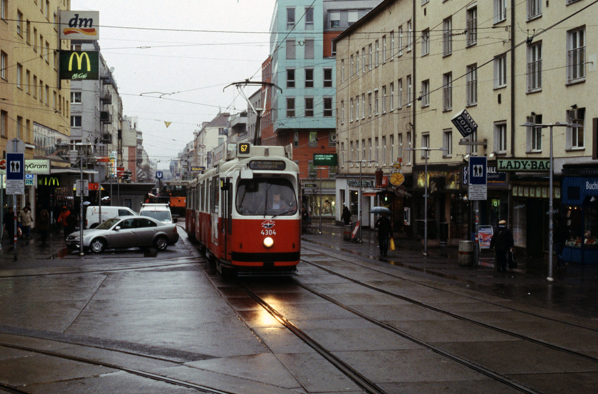 Wien Wiener Linien: An einem trüben Regentag im Februar 2016 nähert sich eine E2+c5-Garnitur (E2 4084 + c5) auf der SL 67 der Haltestelle Reumannplatz (im 10. Bezirk Favoriten). Der Zug fährt in Richtung Per-Albin-Hansson-Siedlung-Ost. - Scan eines Diapositivs. Film: Fuji RXP. Kamera: Konica FS-1.