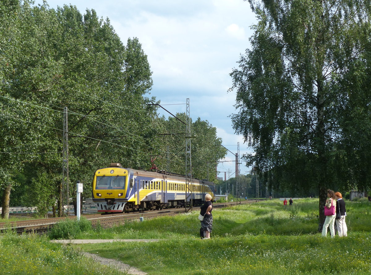 Wilder Bahnübergang in Lettland: Trotz der Kurven und relativ hohen Geschwindigkeiten sind hier Betonplatten im Gleisbereich verlegt, Warnschilder rufen zum Beachten der Züge auf. Auf Bahnhöfen überquert man die Gleise dort, wo es passt, das wird vom Personal toleriert. ER2T-7114-07R am 8.8.2016 in Riga Sarkandaugava