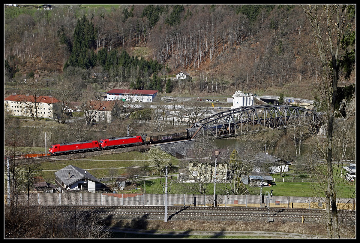 Zwei 185er sind am 6.04.2018 mit einem Güterzug am Brucker Schleifengleis Richtung Süden unterwegs. Gut zu sehen ist die Bogenbrücke über die Mur, die beiden Gleise im Vordergrund  ist die Südbahn.