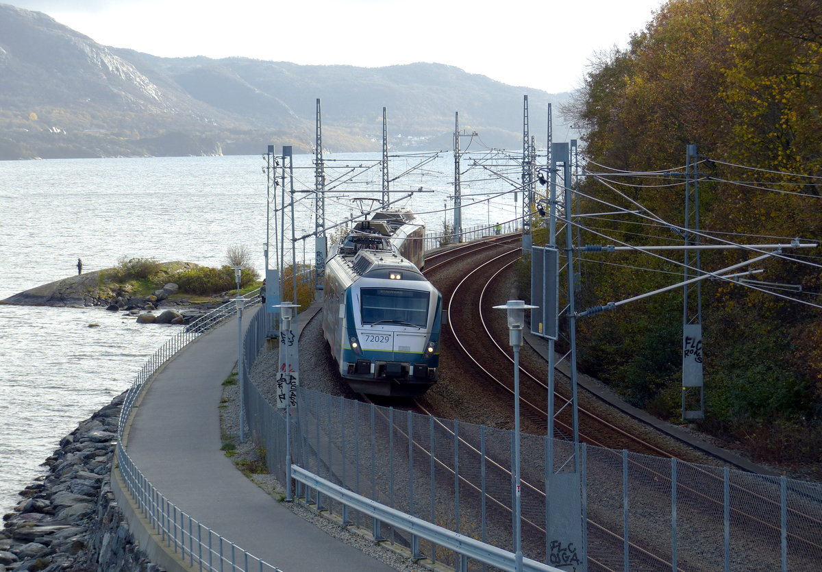 Zwischen Hillevåg und Mariero schlängelt sich die Bahnstrecke an einer Bucht entlang. Hier passiert Fahrzeug 72029 eine Fußgängerbrücke, die sich um Fotografieren gut eignet. 25.10.2018, nahe Stavanger