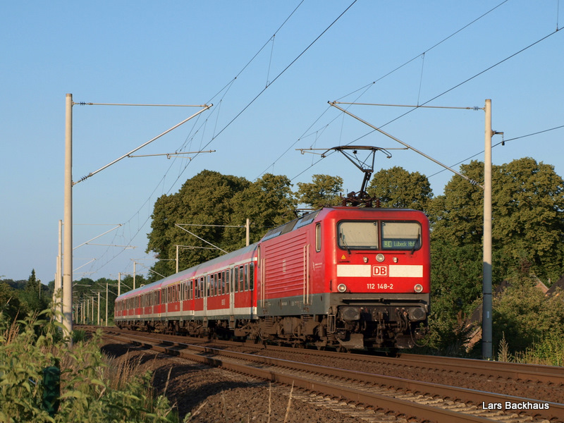 112 148-2 schiebt den RE 21580 aus Hamburg Hbf ber Bad Oldesloe und Reinfeld nach Lbeck Hbf. Aufgenommen am 2.07.09 kurz vorm Halt in Reinfeld (Holst.).