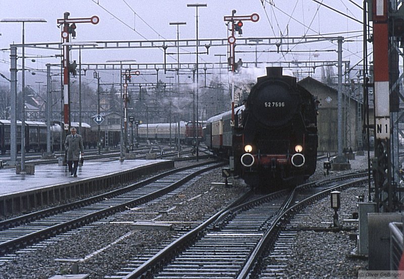 Alles historisch hier in Konstanz. Mindestens 25 Jahre her, etwa 1980-1984 (vielleicht finde ich es noch genauer raus). Zu der Zeit war Dampfverbot bei der Bundesbahn. Deshalb war die Fahrt mit der 52 7596 auf der Mittelthurgaubahn angesagt. Die damals historische 52 ohne Dreilichtspitzensignal mit illustrem Fahrzeugpark bei der Einfahrt in den Bahnhof Konstanz. Heute auch historisch: die Formsignale, alle Gleise rechts des Zuges, der Lokschuppen, das Stellwerk und die altrote 260 im Hintergrund, die wahrscheinlich einen Schnellzug aus Offenburg (vlt. Stuttgart) in die Abstellgleise rangiert.
