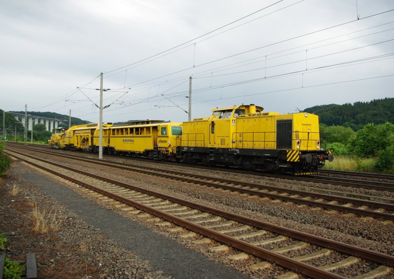 Ein gelber Farbklecks vor grauer Tristesse: V150.04 mit Bauzug zwischen