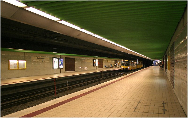 Charlottenplatz U1, U2, U4, (U11) - 

Als erster U-Bahnhof in Deutschland außerhalb von Berlin und Hamburg, ging am 10. Mai 1966 die untere Ebene am Charlottenplatz in Betrieb. Die Station liegt in der 2.ten Tiefebene paralell zu einem Straßentunnel. Zugänge gibt es an beiden Seiten, an der Südseite sind die Verbindungen zur höher liegenden 1967 eröffneten Bahnsteigebene der Talquerlinien, die hier rechtwinkelig kreuzen. Die Station wurde sehr schlicht gestaltet, nur noch die Wandverkleidungen sind von 1966 erhalten. In den achziger Jahren wurde die neue grüne Abhängdecke eingebaut, die Hochbahnsteige entstanden 1988, die 2004 auf die gesamte Bahnsteiglänge ausgedehnt wurden. Schon dieser erste Bahnhof wurde stützenfrei ausgeführt, was die eigentlich die Regel ist in Stuttgart. Die Bahnsteiglänge ist mit 90 m kürzer als die danach entstanden Bahnhöfe, die für eine Dreifachtraktion der für einige Zeit vorgesehenen echten U-Bahn eine Länge von 115 m erhielten. Die U-Bahn wäre der Münchner U-Bahn sehr ähnlich gewesen, auch mit der Wagenbreite von 2,90 m, worauf die Tunnels ausgelegt wurden. 

27.06.2006 (M)