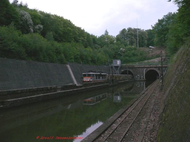 Die BB16638 mit einem Wendezug unterwegs als TER30349 Metz-Sarrebourg-Strasbourg.
Der Bahntunnel von Arzviller wurde zwischen 1846 und 1850 erbaut. Sein Westportal liegt direkt parallel mit dem des Tunnels des Rhein-Marne-Kanals, welcher zeitgleich errichtet wurde. Rechts des Kanaltunnels liegen noch die Schienen der seit vielen Jahrzehnten eingestellten Treidelbahn, mit der frher die Kanalschiffe gezogen wurden. Dies ist eine ziemlich einmalige Sitation, die sich hier an der Vogesenquerung findet.

05.05.2007 Arzviller-Tunnel 