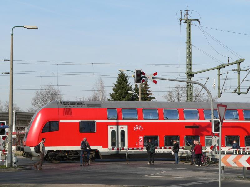 Ein Regionalexpress aus Frankfurt (Oder) fhrt in Frstenwalde ein. Derweil warten Passanten, dass die den Bahnbergang berqueren knnen. April 2005