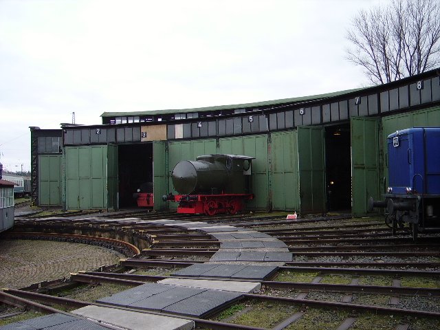 Eine kleine Dampfspeicher Lok in Darmstadt Kranichstein vor dem Lokschuppen. An der rechten Seite sieht man die Schnauze der
V 62 von Museum. 