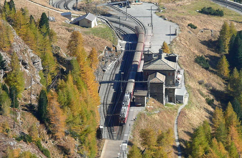 RhB - Regionalzug 1656 von Tirano nach St. Moritz am 12.10.2008 in Alp Grm mit Triebwagen ABe 4/4 II 48 + ABe 4/4 II 45 - BD - A - B - B - B - B - B. Blick auf den im Steilhang liegenden Bahnhof mit 3 Gleisen.
